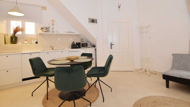 A compact kitchen with a dining area, featuring a round table with chairs, a hanging light fixture, and a coat rack. - Modern and Cozy Rovinj Old Town Apartments - Studio Apartment (Rovinj)