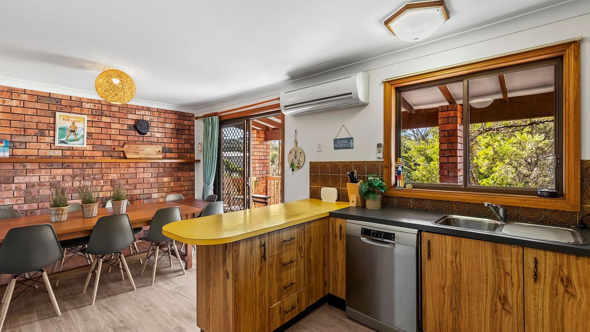 A compact kitchen with wooden cabinetry, a yellow countertop, and a built-in dishwasher.