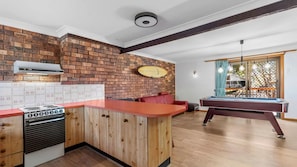 Eine Küche mit Backsteinwand, einem Gasherd und einem Billardtisch im angrenzenden Raum.