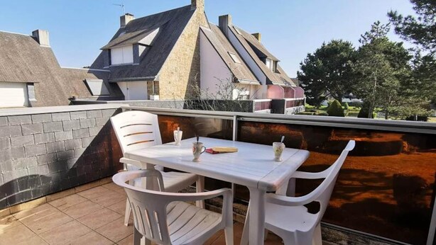 Een terras met een tafel en stoelen, een bakstenen muur en een uitzicht op huizen op de achtergrond.