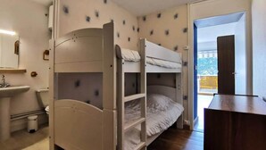 Een slaapkamer met een stapelbed, een wastafel en een kleine prullenbak.