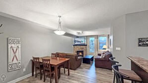 A modern living room with a dining area, fireplace, and a sign reading "Stay In".