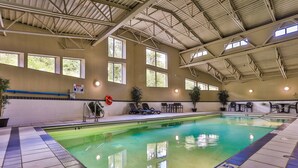 An indoor swimming pool with clear water, tiled floor, and a roof structure.