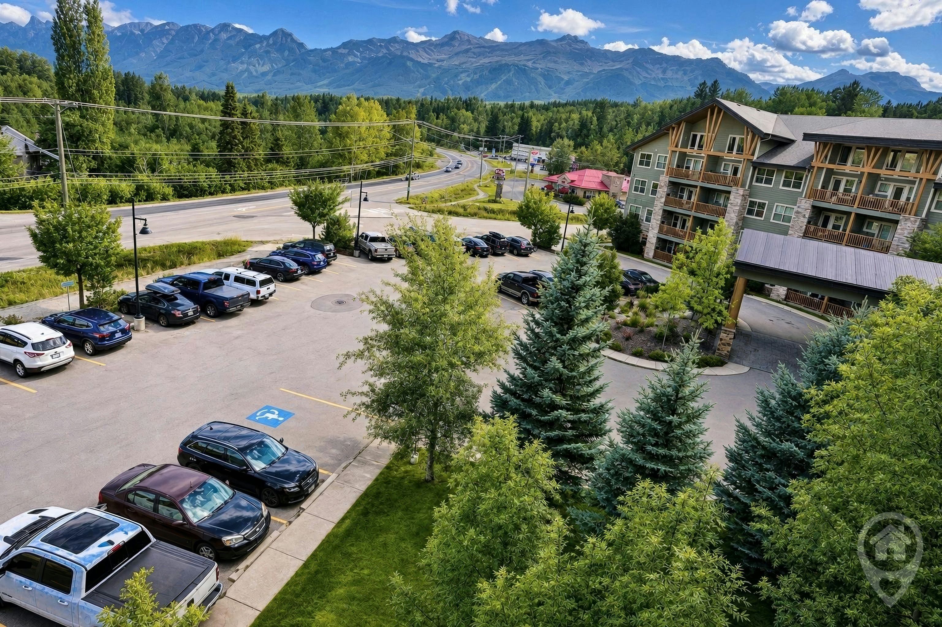 A parking lot with several cars, a building with a red roof, and a mountainous backdrop.