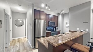 A modern kitchen with a stainless steel refrigerator, microwave, stove, and granite countertop.