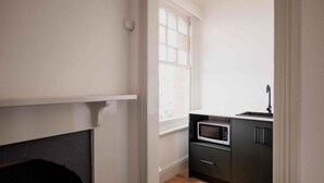 Cozinha compacta com micro-ondas, armários escuros e janela que oferece luz natural.