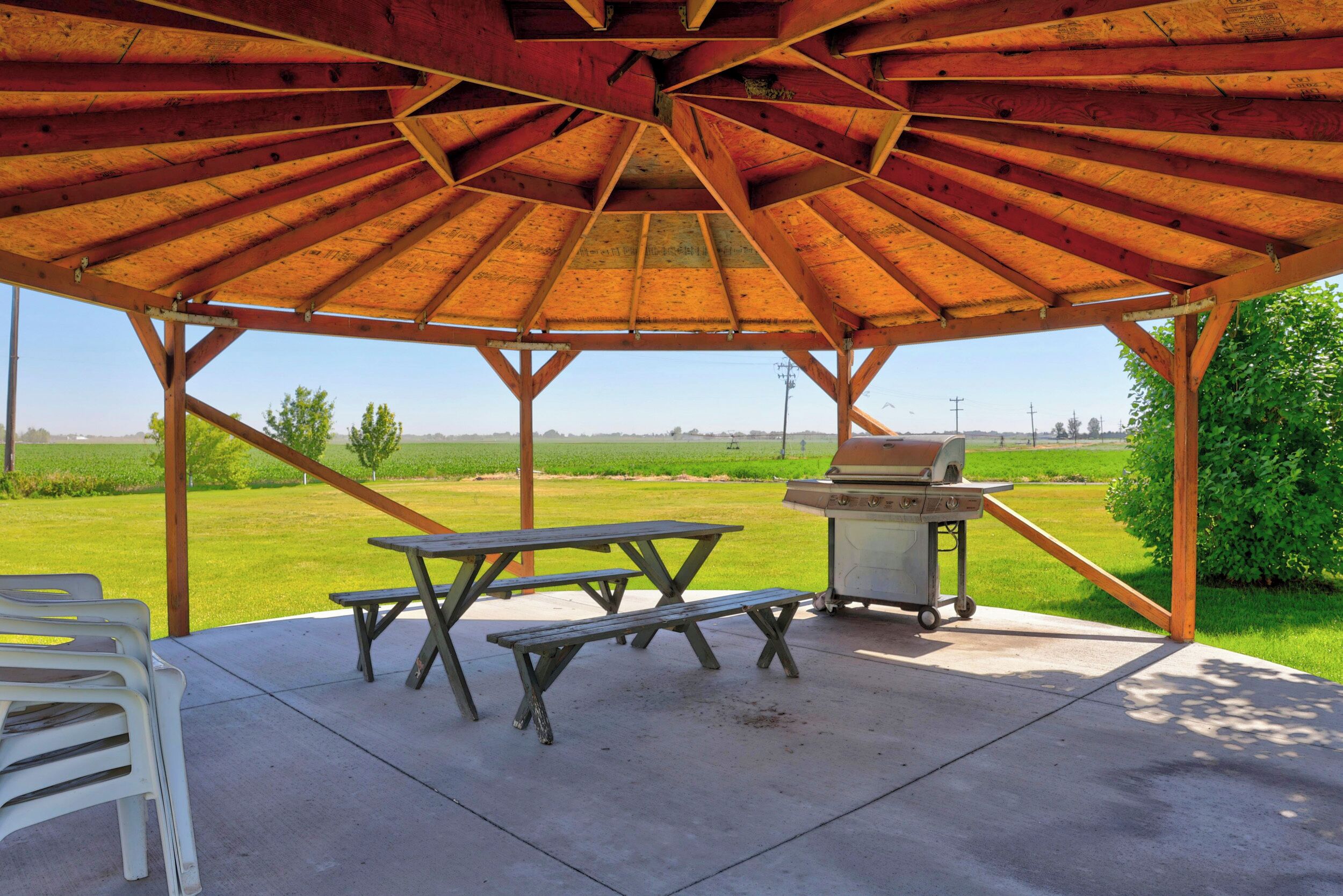 A covered outdoor area with picnic tables and a grill.