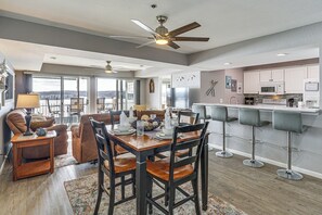 A spacious living area with a dining table, comfortable seating, a kitchen with modern appliances, and a large window offering a view. - ‘Harbour Horizon’ Gem: 1 MM Main Channel, 2 Pools (Lake Ozark)