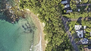 An aerial view of a coastal area with a beach, dense greenery, and residential buildings. - Sting Ray Bay near Boat Harbour Beach (Bendalong)