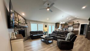 A spacious living room with a fireplace, two sofas, a coffee table, and a kitchen in the background.