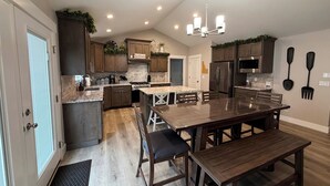 A modern kitchen with dark wood cabinets, a central island, and a dining area with a wooden table and benches.