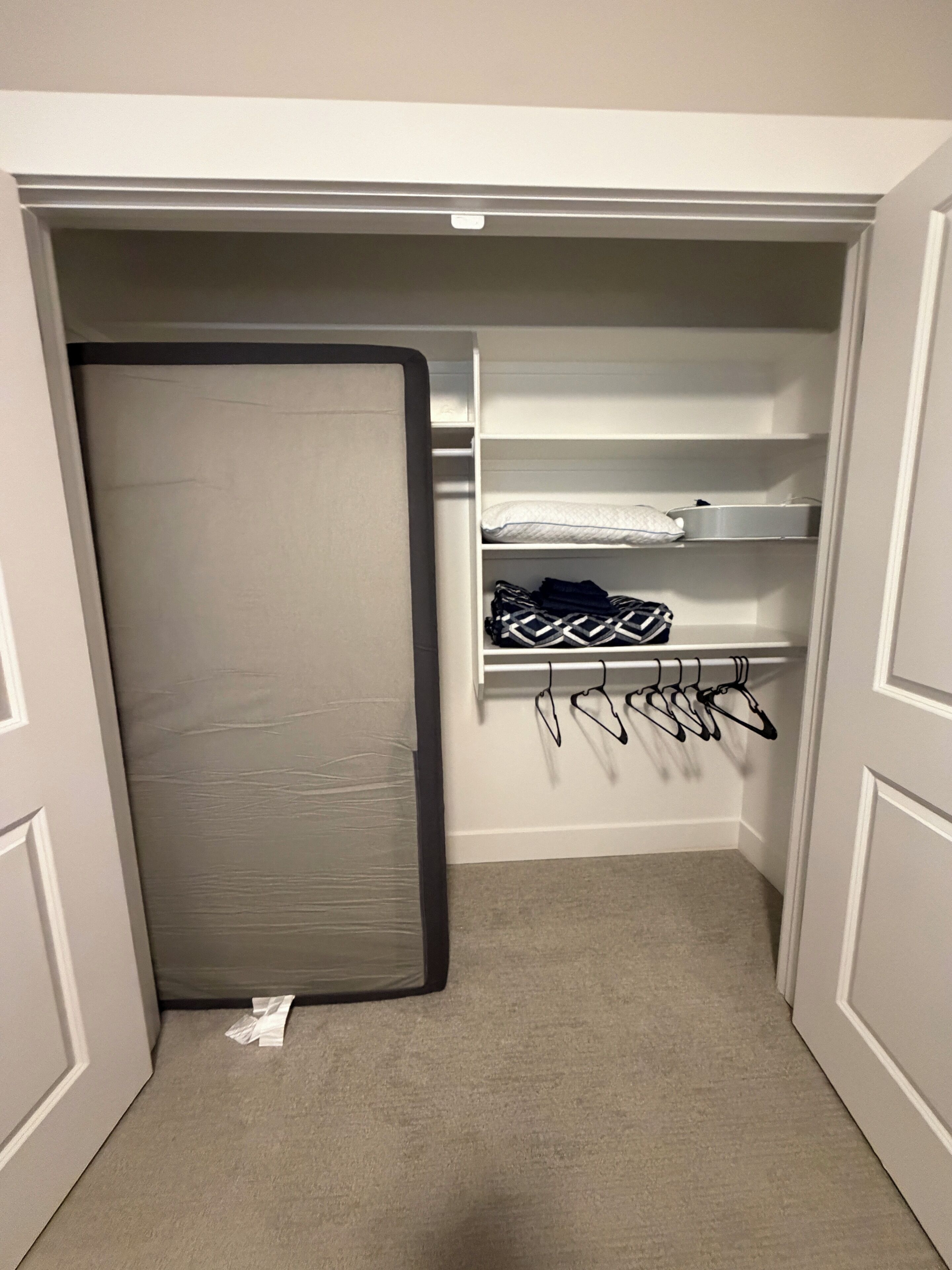 Kävelysäiliö, jossa on peilillä varustettu kaapin ovi, hyllyjä ja tilaa vaatteiden ripustamiseen.
