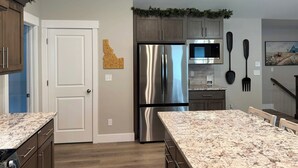 A modern kitchen with a stainless steel refrigerator, a microwave, and a dining area with a granite countertop.
