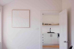 A modern kitchen with white cabinets, a black faucet, and a microwave. - Palfreymans Arcade | Central NoHo 2 Bed Apartment - 6 (Hobart City)