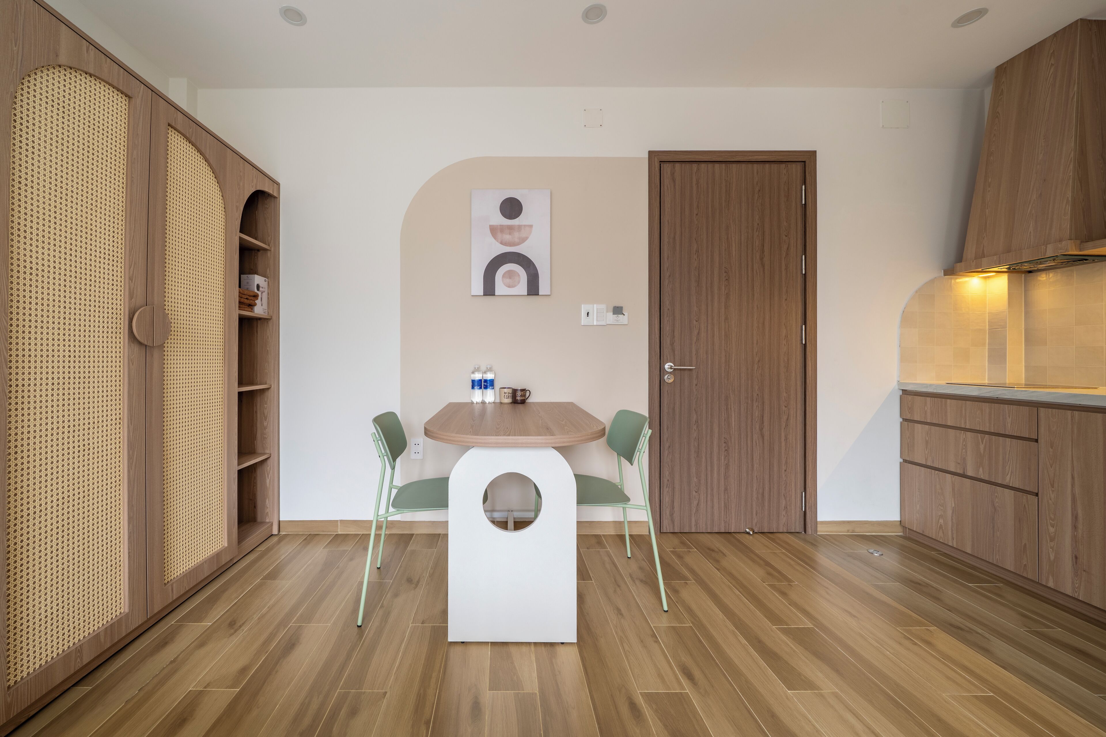 A compact kitchen with wooden cabinets, a round table, and two chairs.