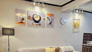A modern living room with a beige sofa, a glass coffee table, and wall art. - Cozy Biñan Getaway - Entire House for Rent (Biñan City)