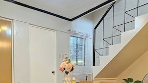A dining area with a wooden table, brown chairs, and a vase of flowers. - Cozy Biñan Getaway - Entire House for Rent (Biñan City)
