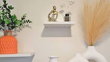 A wall with three white shelves displaying various decorative items.
