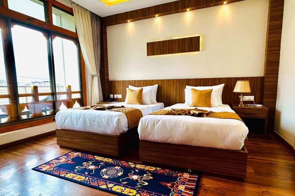 A hotel room with two beds, a large window, and a view of the city.