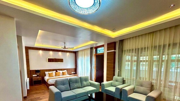 Una habitación de hotel moderna con una cama grande, dos sofás, una mesa de centro y una televisión.