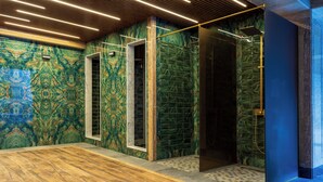 A modern bathroom with a wooden floor, green marble walls, and a glass shower enclosure. - Aivazovsky (Gyumri)