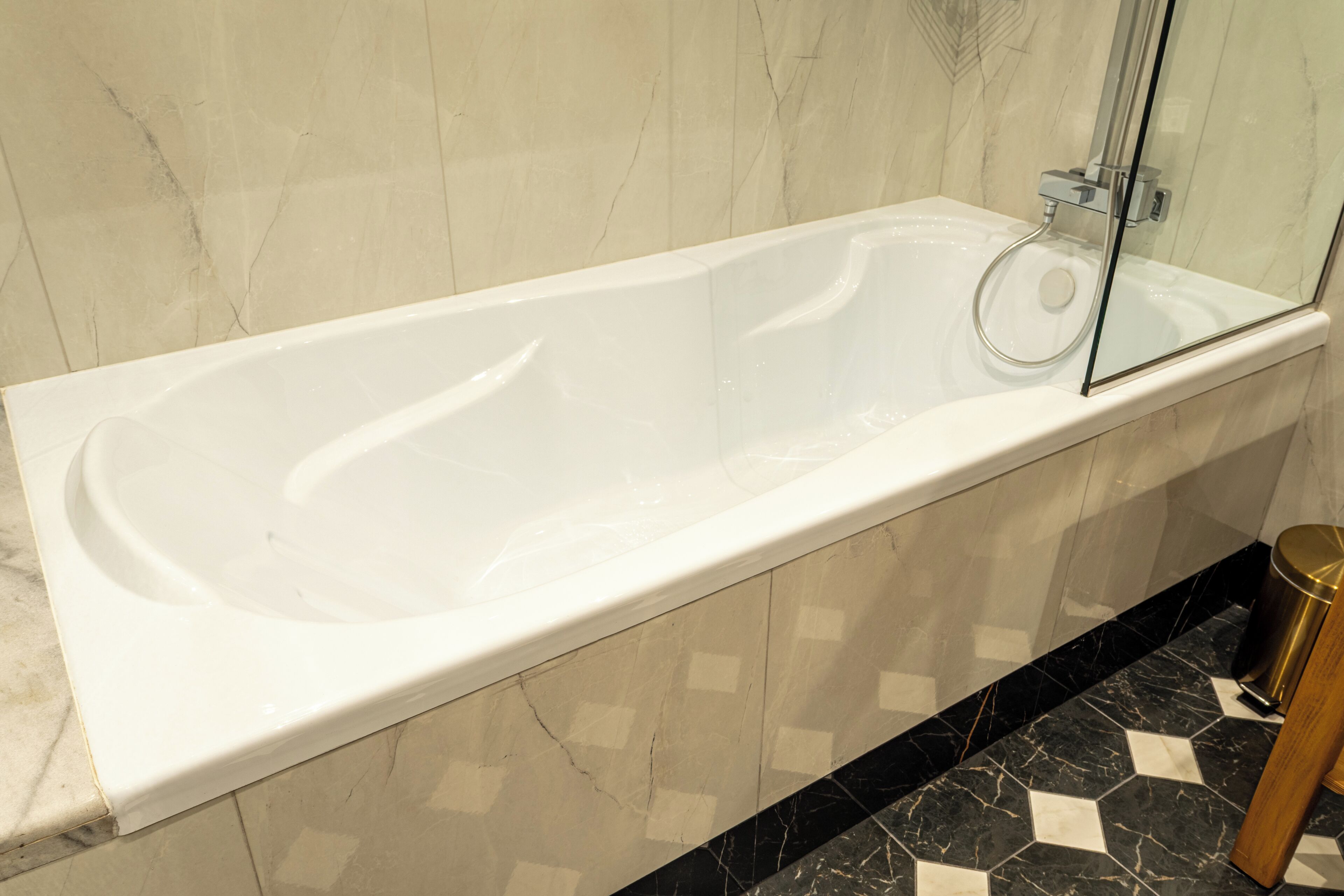 Une salle de bain moderne avec une grande baignoire, une douche à l’italienne avec des parois en verre et un sol en marbre.