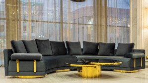 A modern living room with a sectional sofa, a round coffee table, and a large window with a view. - Aivazovsky (Gyumri)