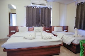 A hotel room with two beds, a mirror, an air conditioner, and curtains. - Shivpriya Palace (Deoghar)