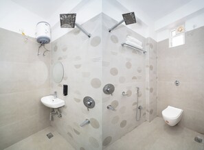 A modern bathroom with a shower, sink, and toilet, featuring a unique polka dot tile pattern. - Shivpriya Palace (Deoghar)