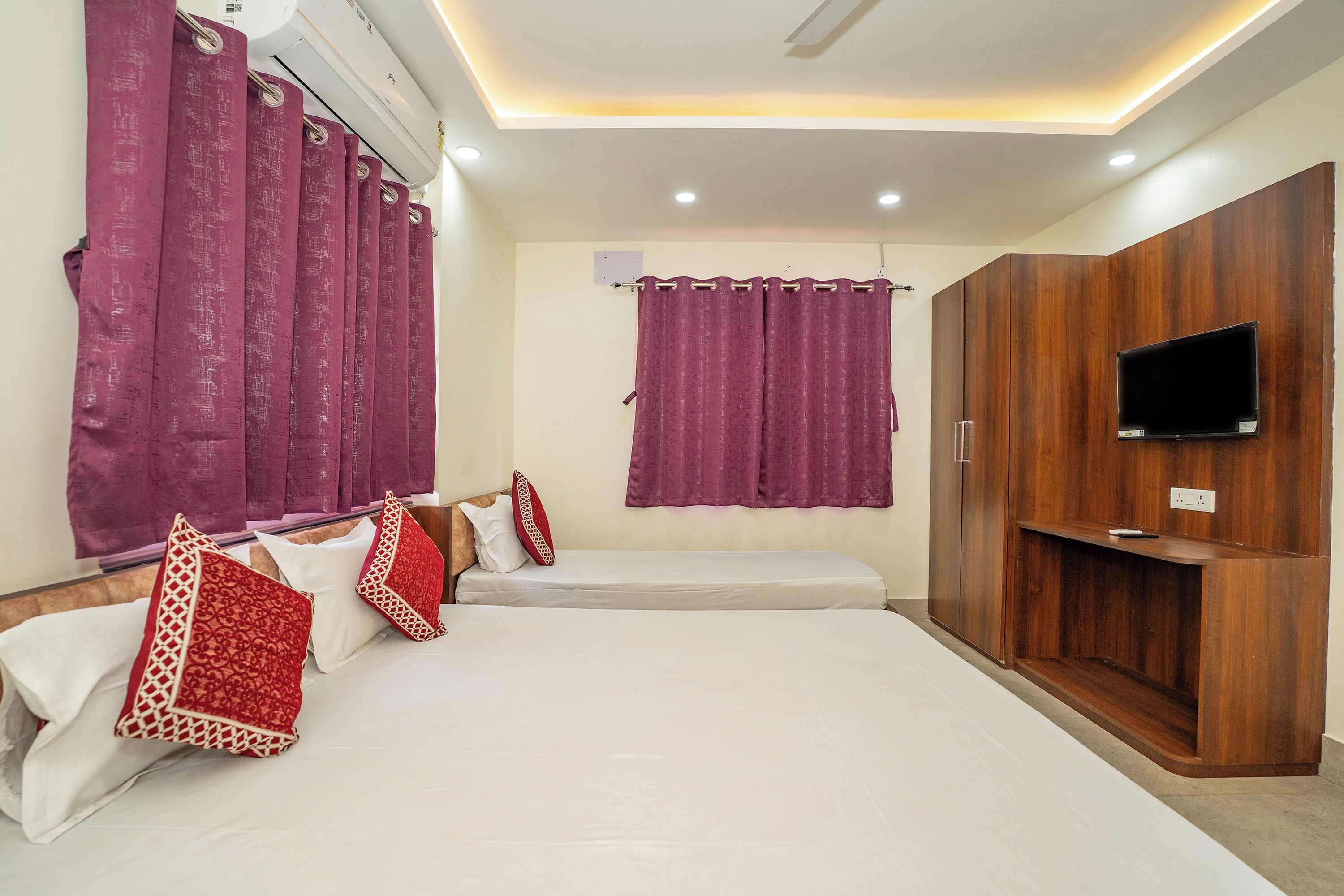 Une chambre d’hôtel avec un lit, une télévision et une armoire.