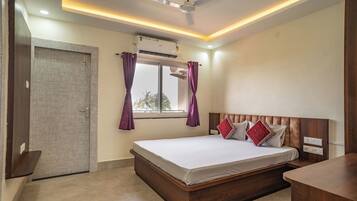 A bedroom with a bed, a ceiling fan, an air conditioning unit, a window with curtains, and a door.