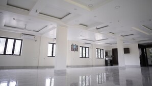 A spacious, well-lit hotel lobby with a polished floor, large windows, and a modern ceiling design. - Shivpriya Palace (Deoghar)