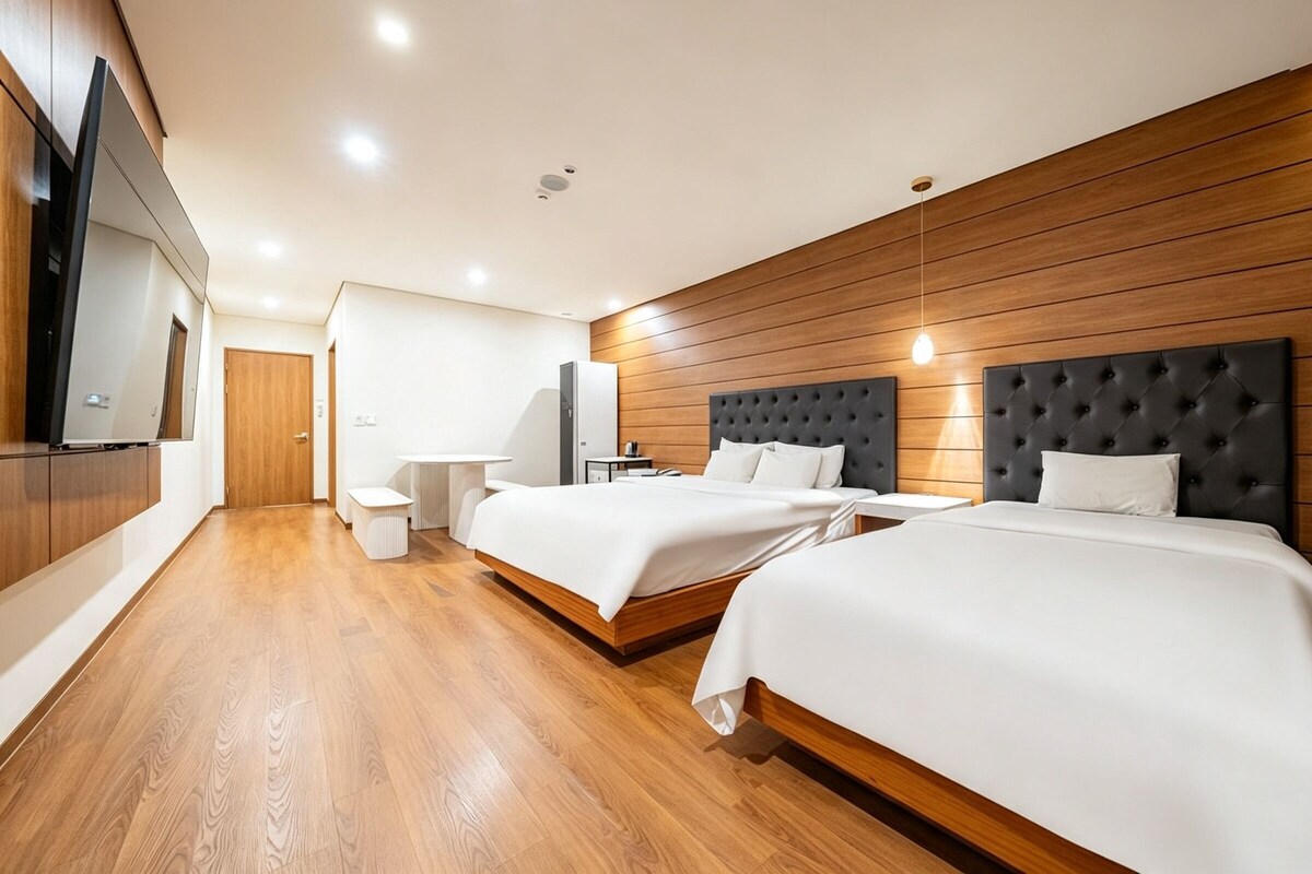 Ein modernes Hotelzimmer mit zwei Betten, einem Flachbildfernseher, Holzwandverkleidung und Holzboden.