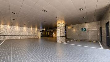 A spacious indoor area with a tiled floor, a stone wall, and a sign indicating an EV charging station.