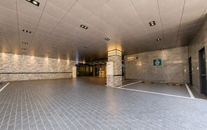 A spacious indoor area with a tiled floor, a stone wall, and a sign indicating an EV charging station. - M Place Hotel Guwol-dong (Incheon)