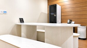 A modern reception area with a white reception desk, a black and white air purifier, and a kettle on the counter. - M Place Hotel Guwol-dong (Incheon)