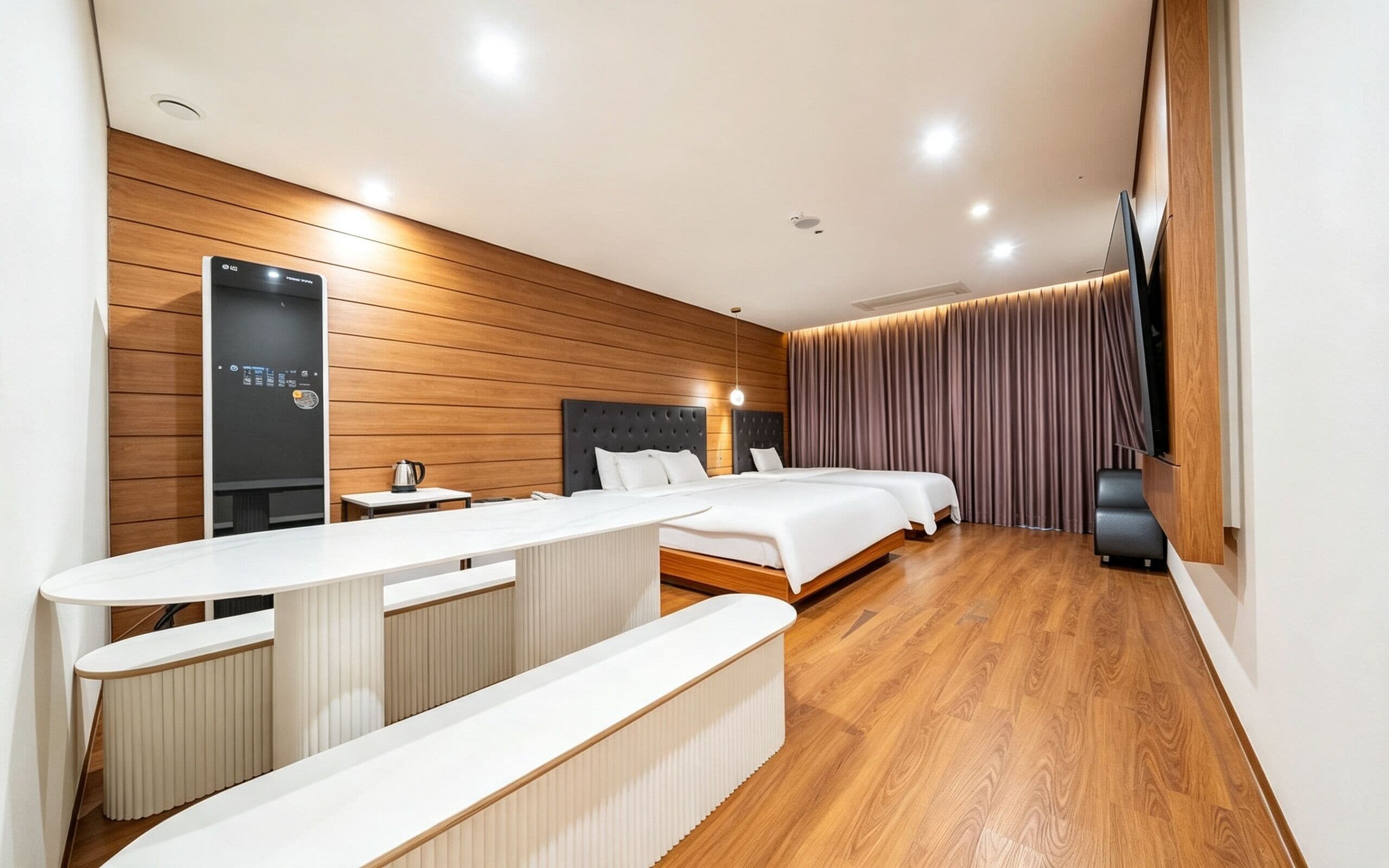 A modern hotel room with a wooden floor, a large bed, a smaller bed, a desk, and a seating area.