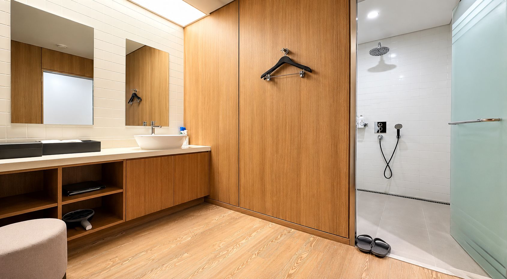 Een moderne badkamer met een houten wastafelmeubel, een grote spiegel en een inloopdouche.