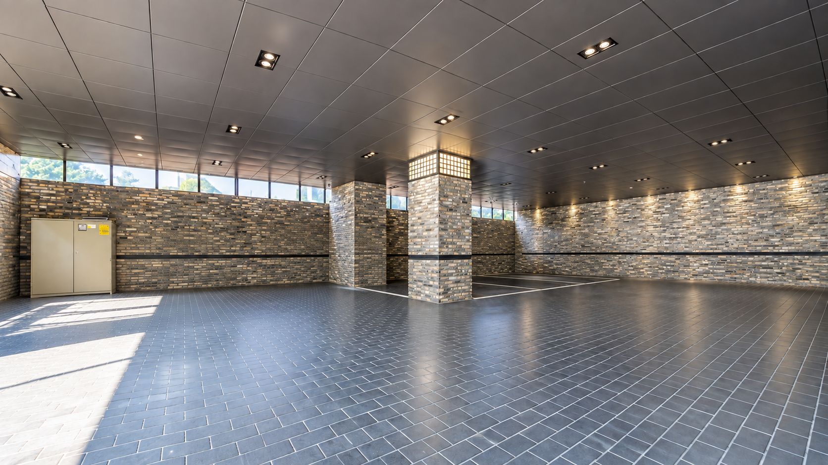 A spacious indoor area with a tiled floor, stone walls, and a door on the left.