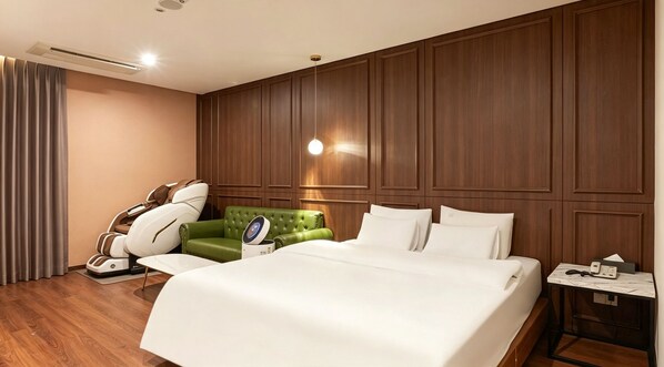 A hotel room with a large bed, a massage chair, a green sofa, and a bedside table with a phone and tissues. - M Place Hotel Guwol-dong (Incheon)