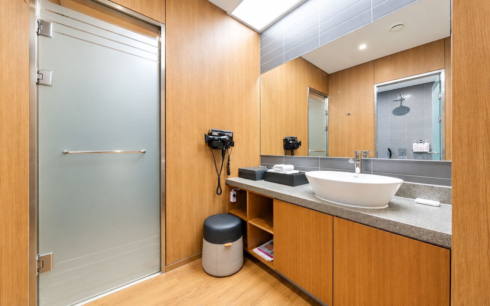 A modern bathroom with a wooden vanity, a large mirror, a sink, and a toilet.