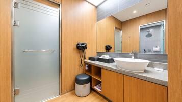 A modern bathroom with a wooden vanity, a large mirror, a sink, and a toilet.