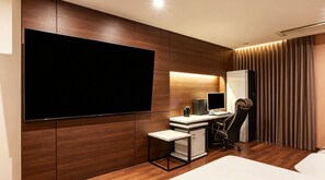 A modern hotel room with a large flat-screen TV, a desk with a computer, a chair, and a small refrigerator. - M Place Hotel Guwol-dong (Incheon)