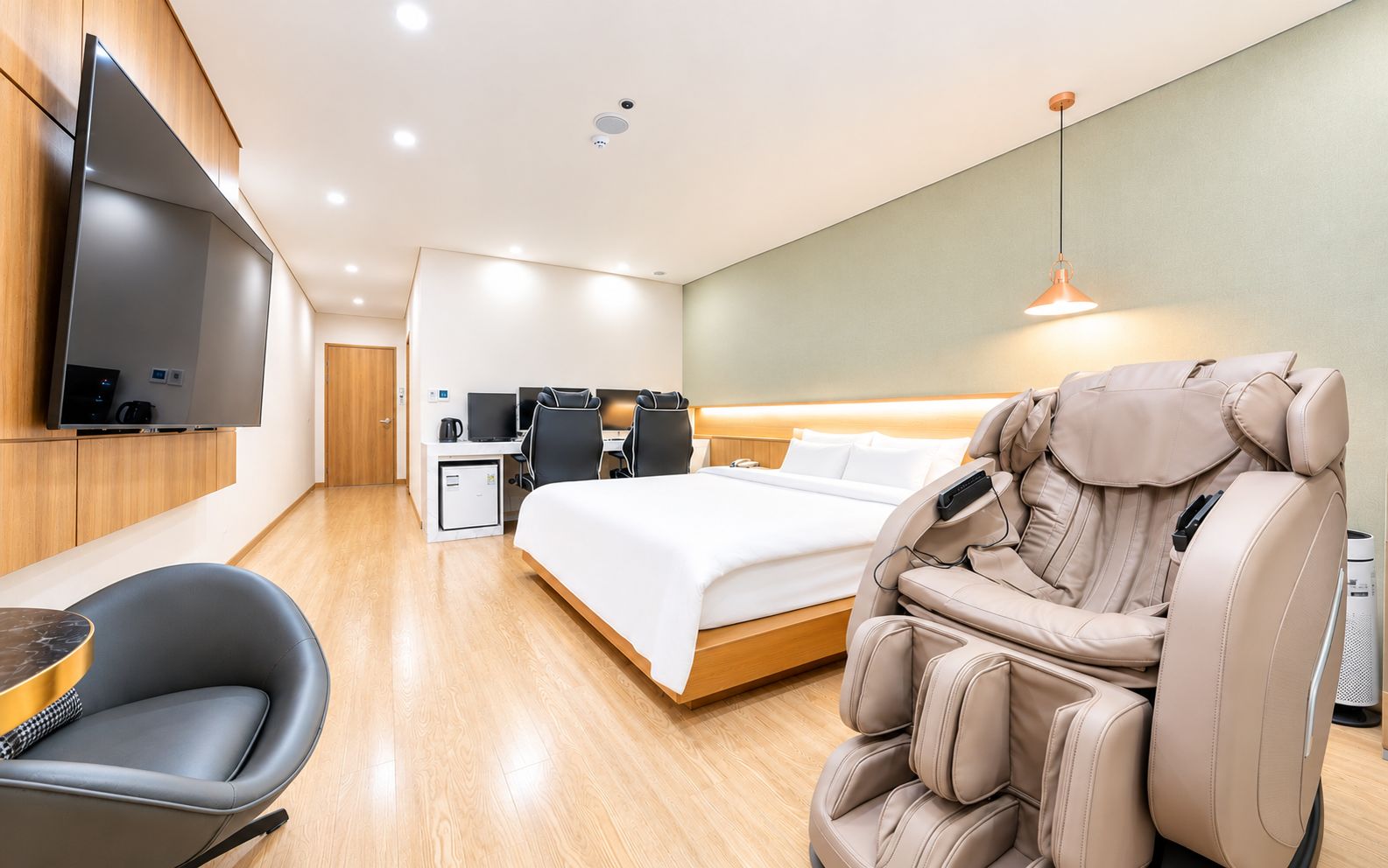 Habitació d'hotel moderna amb llit, cadira de massatge, escriptori i televisió.