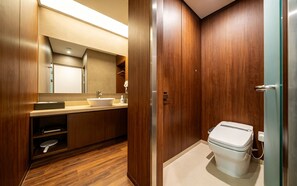 A modern bathroom with a wooden vanity, a sink, a mirror, and a toilet. - M Place Hotel Guwol-dong (Incheon)