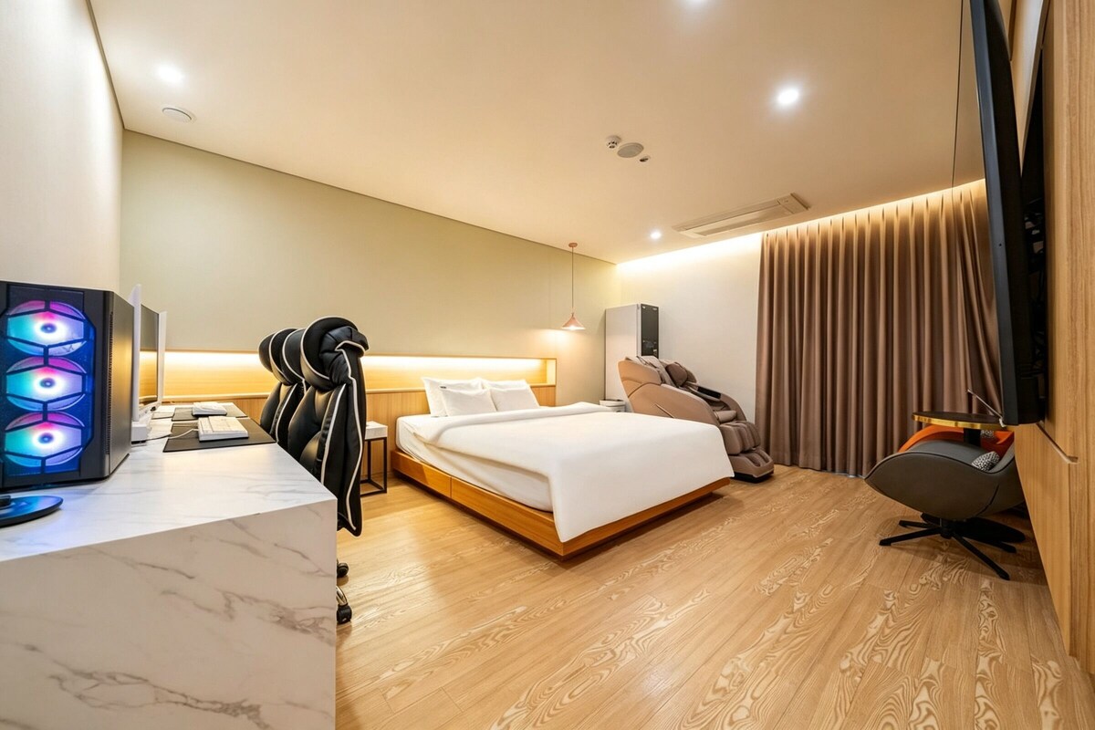 Ein modernes Hotelzimmer mit Bett, Schreibtisch, Stuhl, Massagesessel und Fernseher.