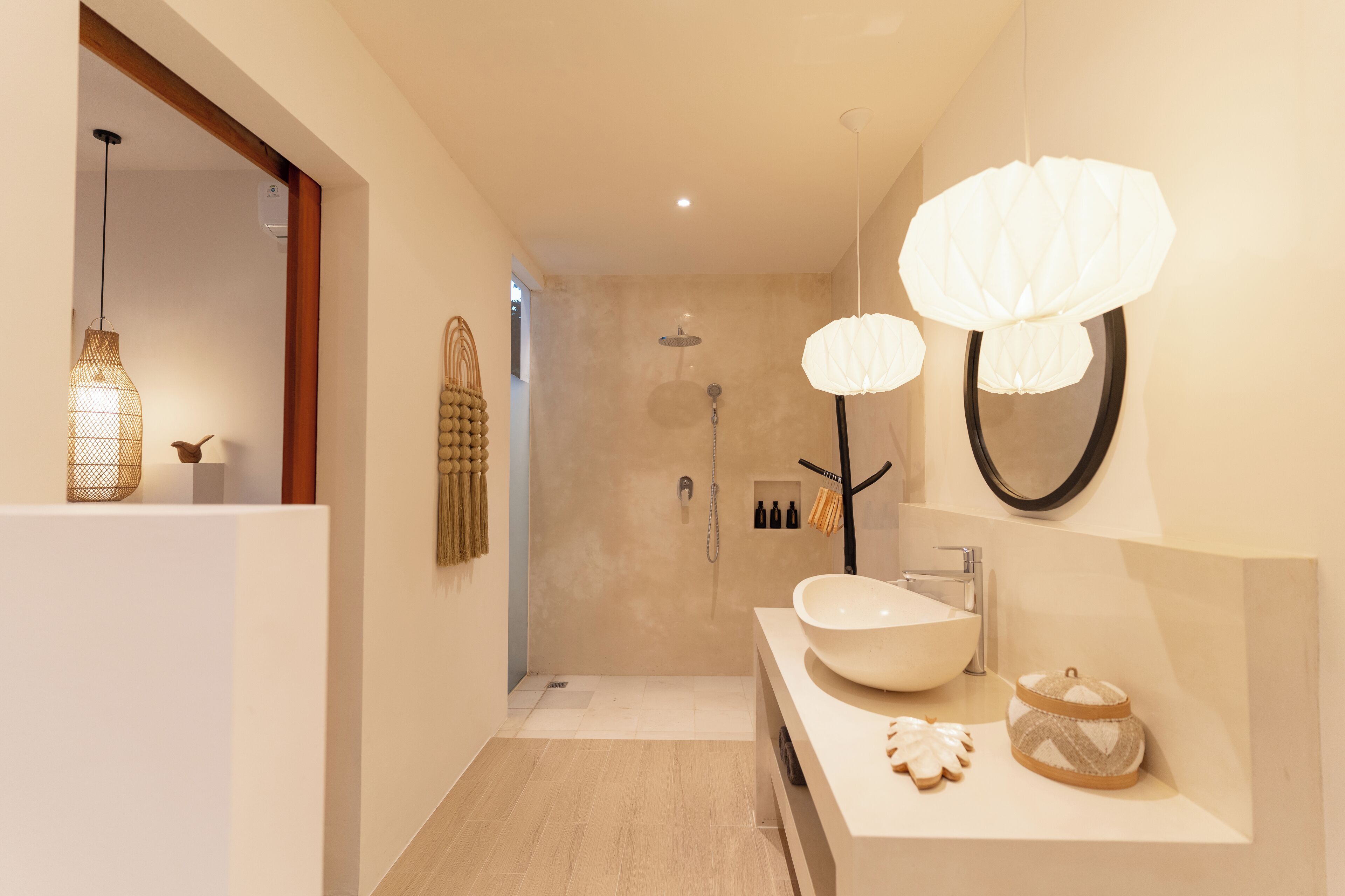 Un baño moderno con un lavabo grande de color blanco, una ducha y un espejo con marco negro.