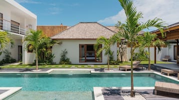 Una piscina al aire libre, sillones reclinables de piscina