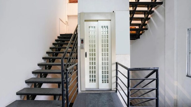 A staircase with black railings leading to a white door with a glass panel. - Hotel Saubhagya Elite (Nashik)