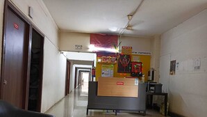 A reception area with a reception desk, a ceiling fan, and a corridor leading to other rooms. - Hotel Saubhagya Elite (Nashik)